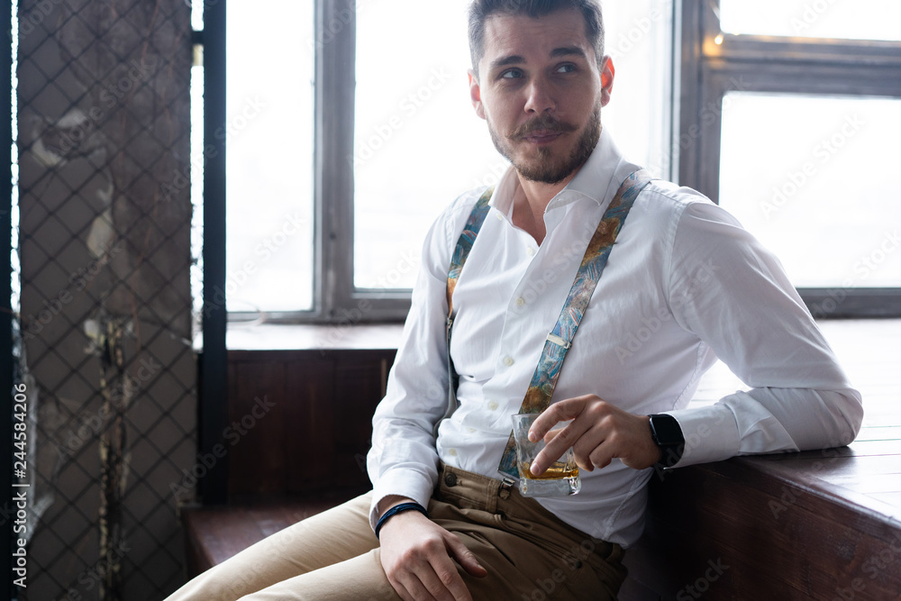 Wall mural feeling lonely. stylishly dressed young man holding a glass while sitting on sofa.