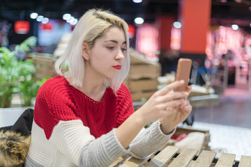 Side view of a young beautiful woman taking a selfie in a bar.