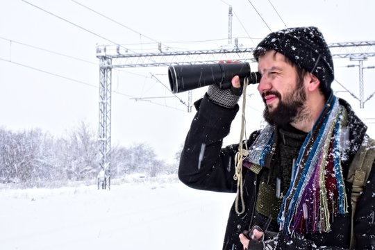 man holding binoculars in snow