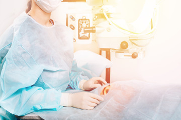 Lasik treatment. Laser vision correction. Doctor examines fundus in microscope, patient under...