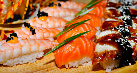 Eating Sushi with chopsticks. Sushi roll japanese food in restaurant. California Sushi roll set with salmon, vegetables, flying fish roe and caviar closeup. Japan restaurant menu