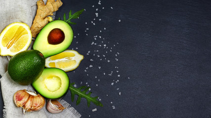 Green vegetables avocados, lemon, ginger, garlic, sea salt, rucola salad on a shale board, the concept of healthy eating, copy space, top view set
