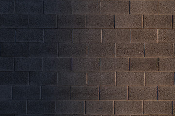 The texture of a brick wall made of blocks of imitation of natural stone, a delightful background with a gradient.         