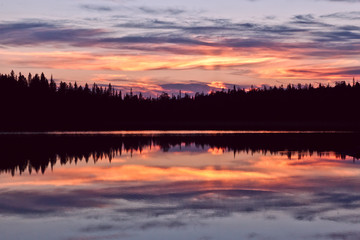 sunset clouds are reflected in the calm mirror water of the lake
