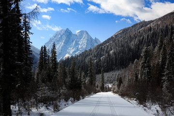 ShuangQiao Valley Scenic Area, Four Girls Mountain National Park in Sichuan Province China. Snow Capped Jagged Mountains and Blue Sky, Snow Mountains, Empty National Park Utility Access Road