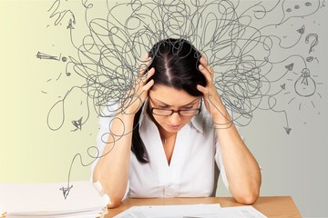 Businesswoman sitting at the table with many papers in office