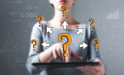 Big and small question marks with arrows with business woman using a tablet computer
