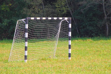 Fototapeta premium Empty football goal in a clearing against the forest on a Sunny summer day - sports, outdoor activities, equipment