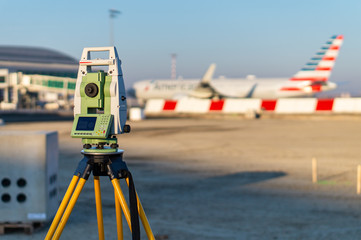 Surveyor equipment (theodolite) on construction site of the airport, building or road with construction machines in background