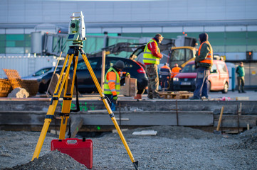 Surveyor equipment (theodolite) on construction site of the airport, building or road with construction machines in background