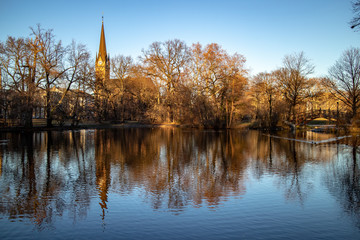 Fototapeta na wymiar Teich im Park mit Romantischen Brücken,Kirche im Winter in Leipzig mit blauen Himmel