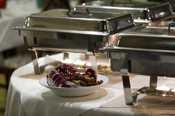 Talerz i patelnie z jedzeniem na stole w restauracji, katering.