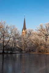 Zugefrorener Teich im Park mit Romantischen Brücken im Winter in Leipzig  bei frostigen Wetter mit blauen Himmel