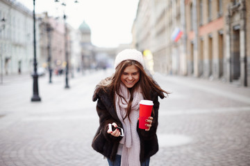 Brunette girl posing for photo in city streets with Christmas mood