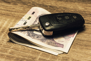 Car keys and banknotes as the concept of buying or renting a car. Loan for buying a car. Czech money at the table. Financial concept with money.