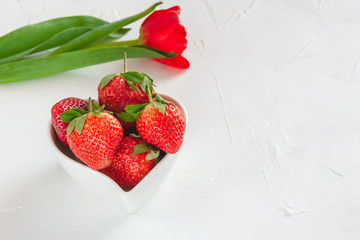Fresh tulips and strawberries in a heart-shaped bowl for Valentine's Day.