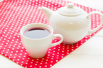 Black tea ceremony - a cup of tea, teapot, flowers on a red with white dots background