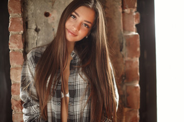 Fototapeta premium Young woman posing indoor with christmas tree in winter decor studio. 