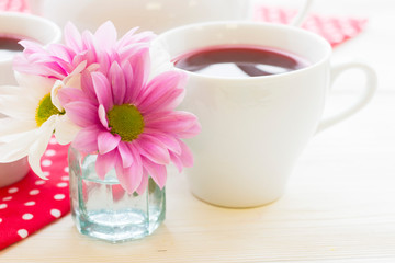 Black tea ceremony - a cup of tea, teapot, flowers on a red with white dots background