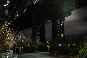 View of the Manhattan Bridge and Manhattan from the riverside of the East River at night  with  the...