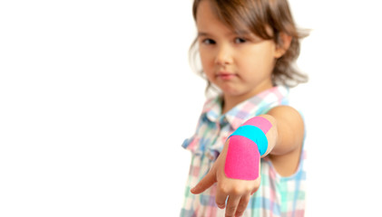 little girl showing her bandaged wrist with kinesio tapes