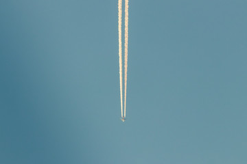 Airplane with condensation trails in the blue sky - 244598675