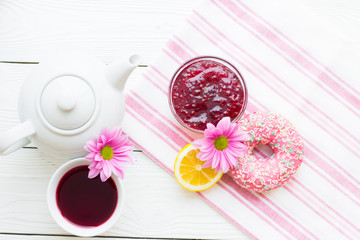 Black tea ceremony - a cup of tea, teapot, sugar, cakes, flowers on white wooden rustic background