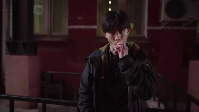Asian teenager Smoking a cigarette on the street in a state of depression walking around the city in the afternoon. Psychological portrait of a man