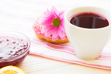 Black tea ceremony - a cup of tea, teapot, sugar, cakes, flowers on white wooden rustic background