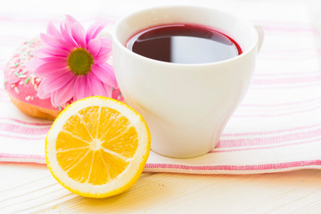 Black tea ceremony - a cup of tea, teapot, sugar, cakes, flowers on white wooden rustic background