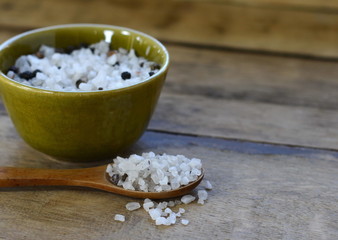 sea salt with pepper and spices . sea salt in bowl with wooden spoon on wooden background.
