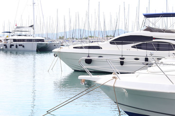 Obraz premium Modern luxury motor cruise yachts on the quay in the marina. Leisure activities of rich people at sea. Water transport for holidays and vacations. Products from plastic and carbon fiber.