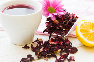 Black tea ceremony - a cup of tea, teapot, sugar, cakes, flowers on white wooden rustic background