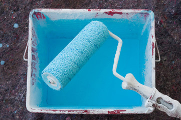 Obraz premium paint roller in a bucket with blue paint