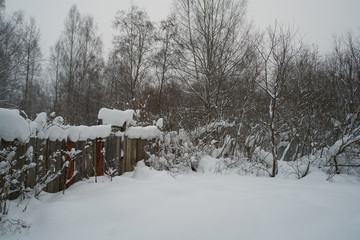 winter fence in the village. piled old snow.