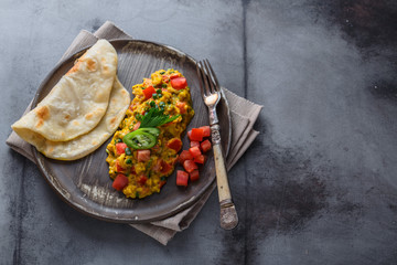 Scrambled eggs with tomatoes and chives on a plate, copy space