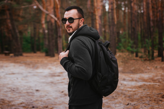 Man with beard in glasses and backpack in the forest