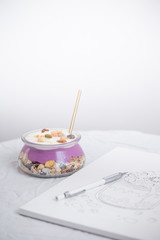 Granola superfood with almond and cashew nuts, dry fruits, raisins cherry in the glass bawl with milk and greek yogurt on the white wood table