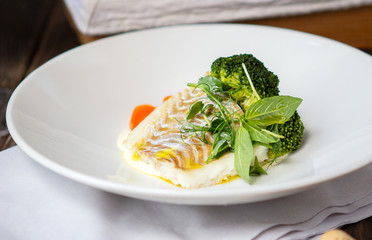 Cod fish fillet with mashed potatoes and broccoli on a white plate
