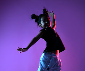 Asian kid girl in shirt and pants with stars dances and jumps