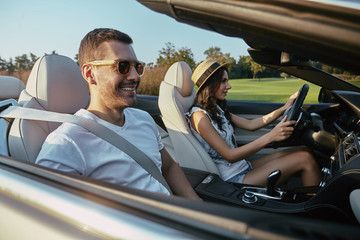 man with girlfriend driving cabriolet