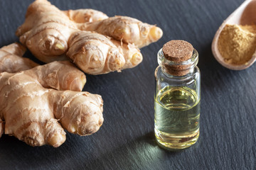 A bottle of ginger essential oil with fresh and ground ginger