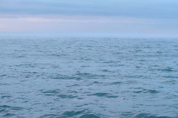 Mist and fog over the sea. Beautiful seascape with pink sunset and blue clouds. Calm sea.