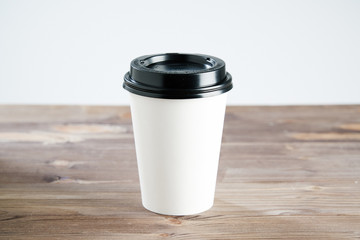 Paper  coffee cup disposable for take away or to go, at wooden table, space for design layout.