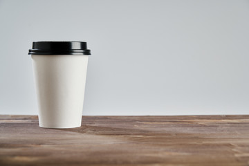  Paper disposable coffee cup for take away or to go, at wooden table, space for design layout.
