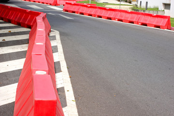 Red and white plastic barriers blocking the road .