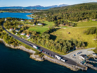 Obraz premium Drone Photo of the Cars Waiting in Line on Ferry Port in Langfjorden in Norway on a Sunny Summer Day with Mountains and Blue Skies in the Background