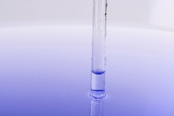 Pipette immerses with liquid in water with reflection