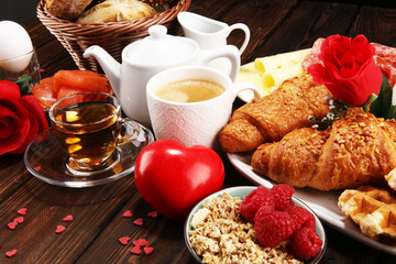 breakfast on table with bread buns, croissants, coffe and juice on valentines day.