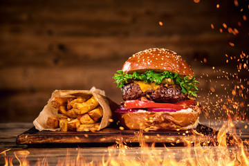 Tasty burger with french fries and fire. - obrazy, fototapety, plakaty